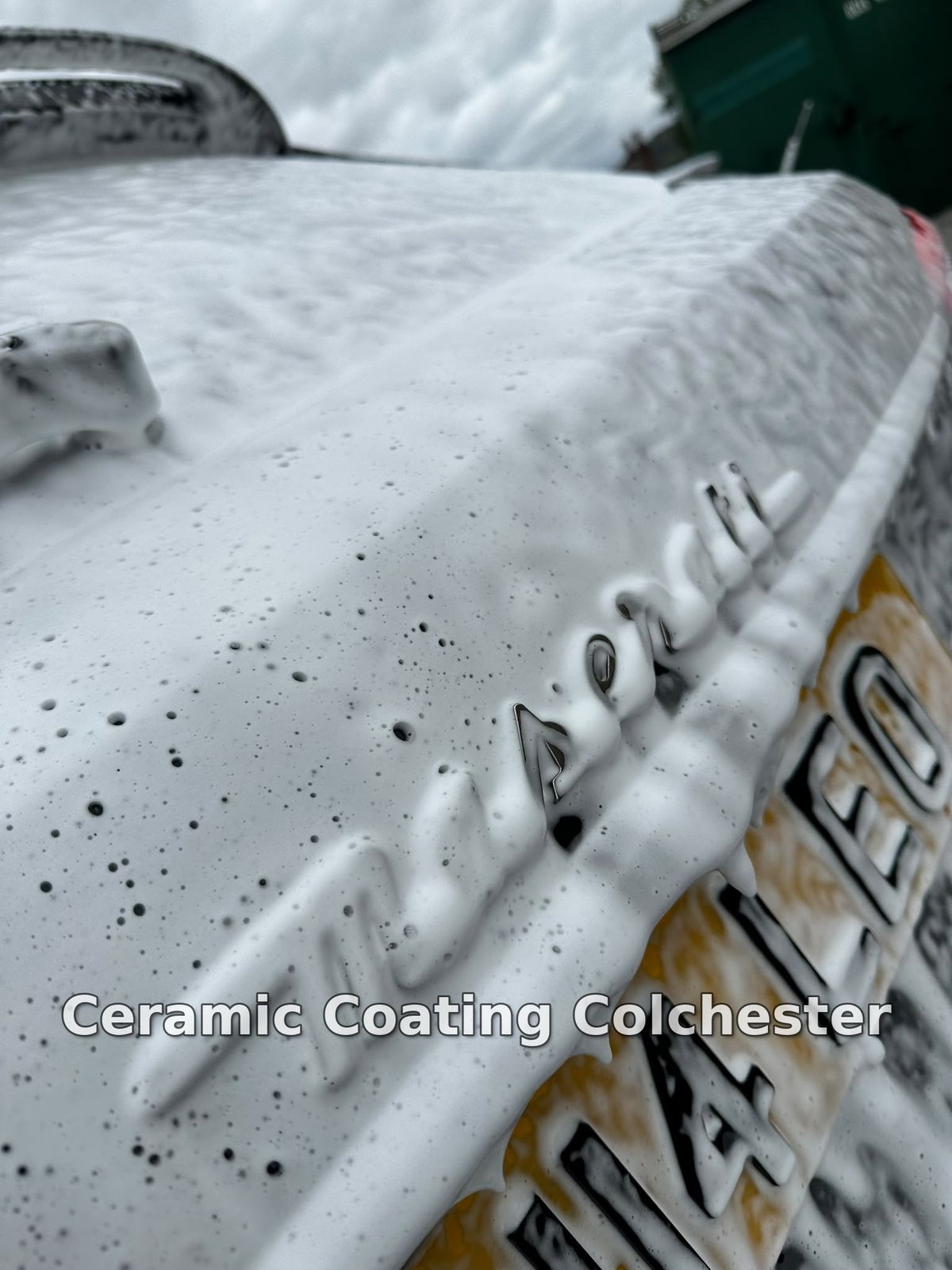 Close-up of a Maserati badge covered in snow foam